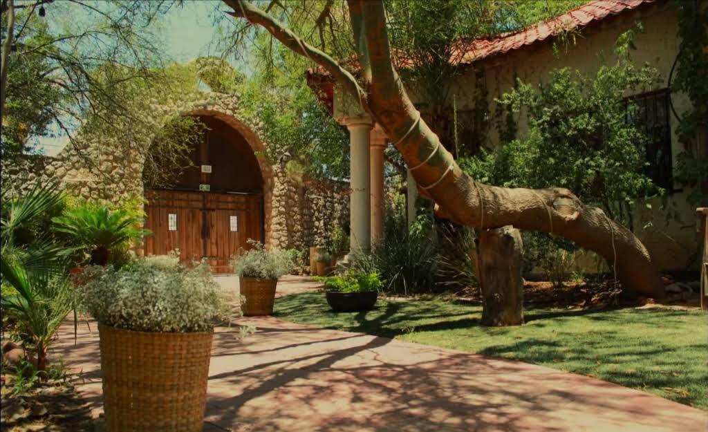 Entrada de piedra de Quinta El Vergel, con puertas de madera y jardines alrededor.
